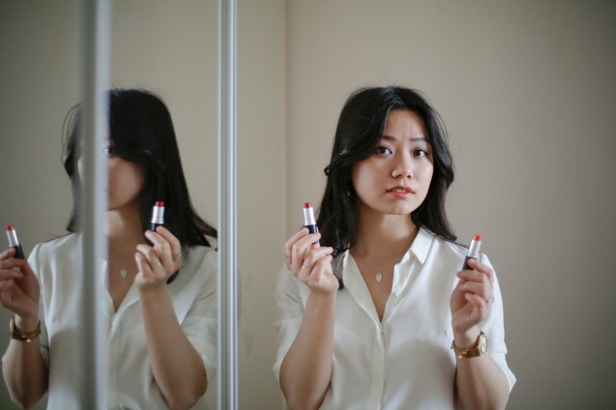 鏡の前で2本の口紅を比べる女性